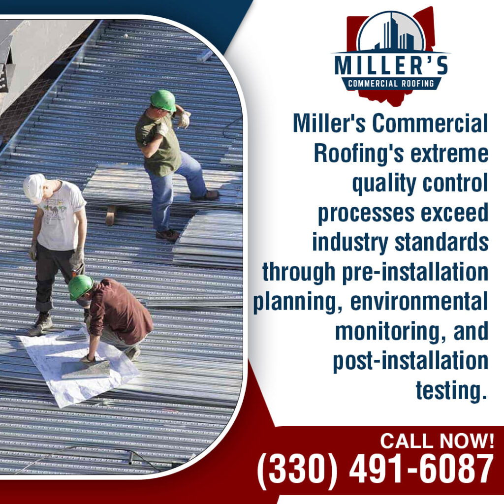 Three commercial roofers on a metal roof, two standing and one kneeling, possibly reviewing plans.