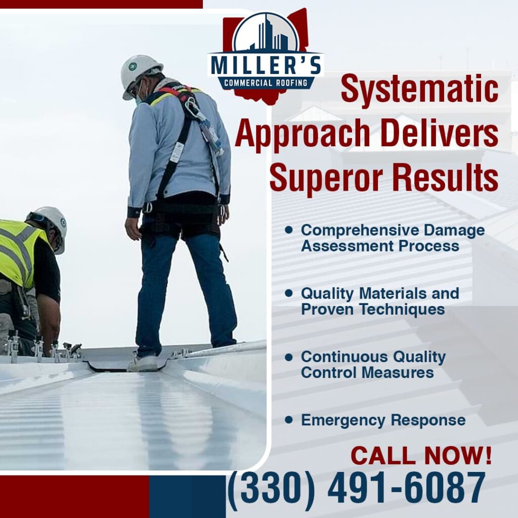 Two roofers working on a white commercial roof. One roofer, wearing a hard hat and safety harness, stands tall while another is bent over, appearing to work on the roof surface.